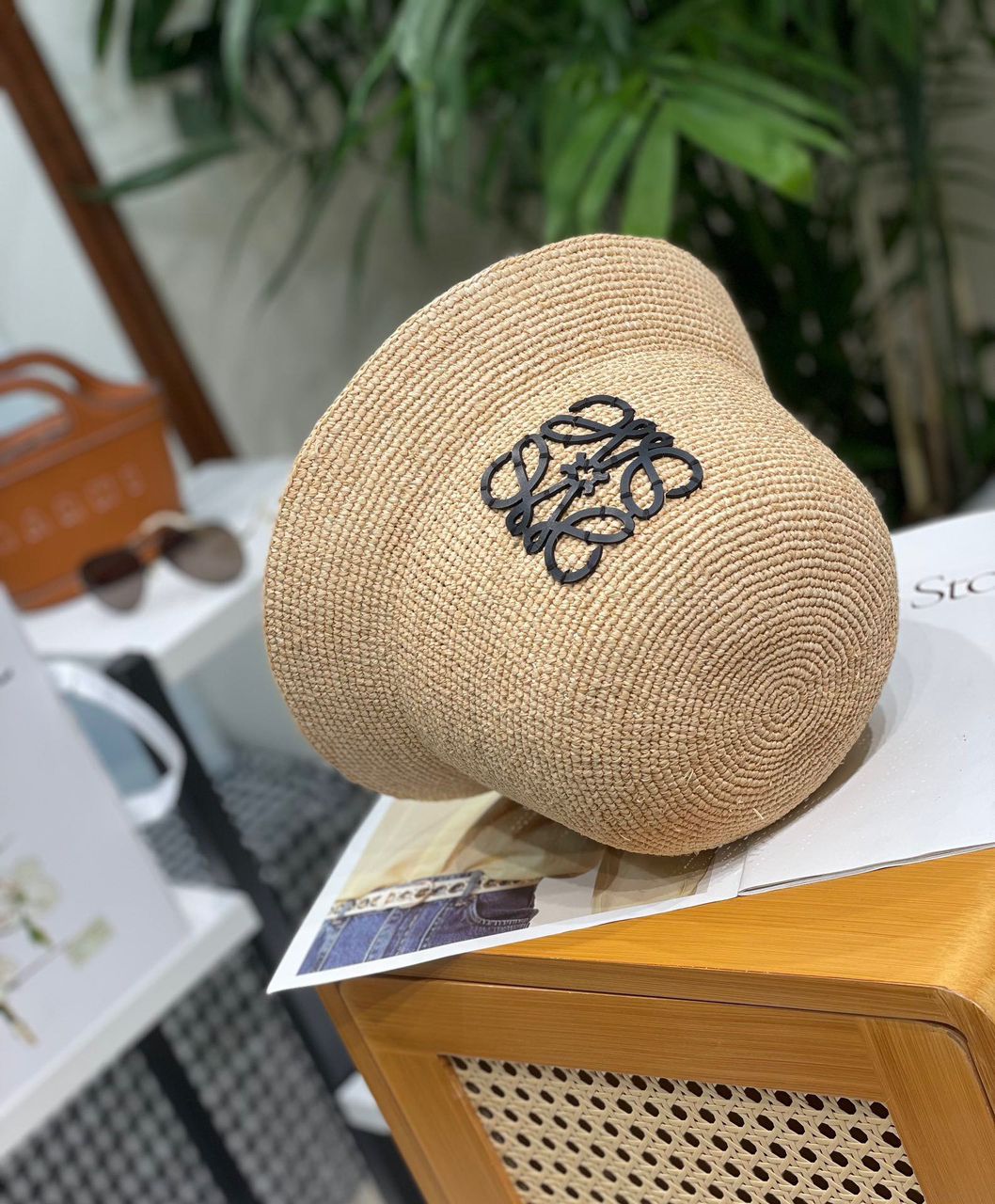 Beige straw hat with a logo on a wooden surface with a blurred background
