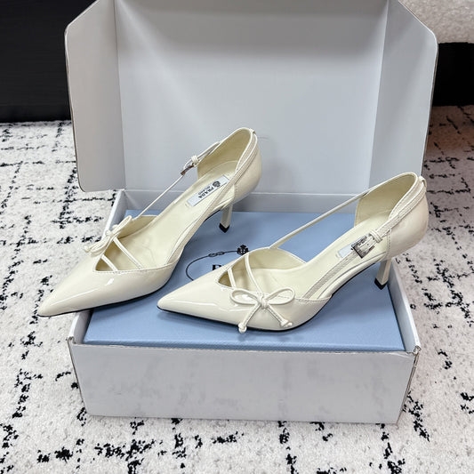 ЖІНОЧІ ТУФЛІ PRADA 26S НА ВИСОКИХ ПІДБОРАХ 75 ММ ІЗ ЗАГОСТРЕНИМ НОСКОМ, ВИГОТОВЛЕНІ З ЛАКОВАНОЇ ТЕЛЯЧОЇ ШКІРИ КОЛЬОРУ СЛОНОВОЇ КІСТКИ, З БАНТОМ