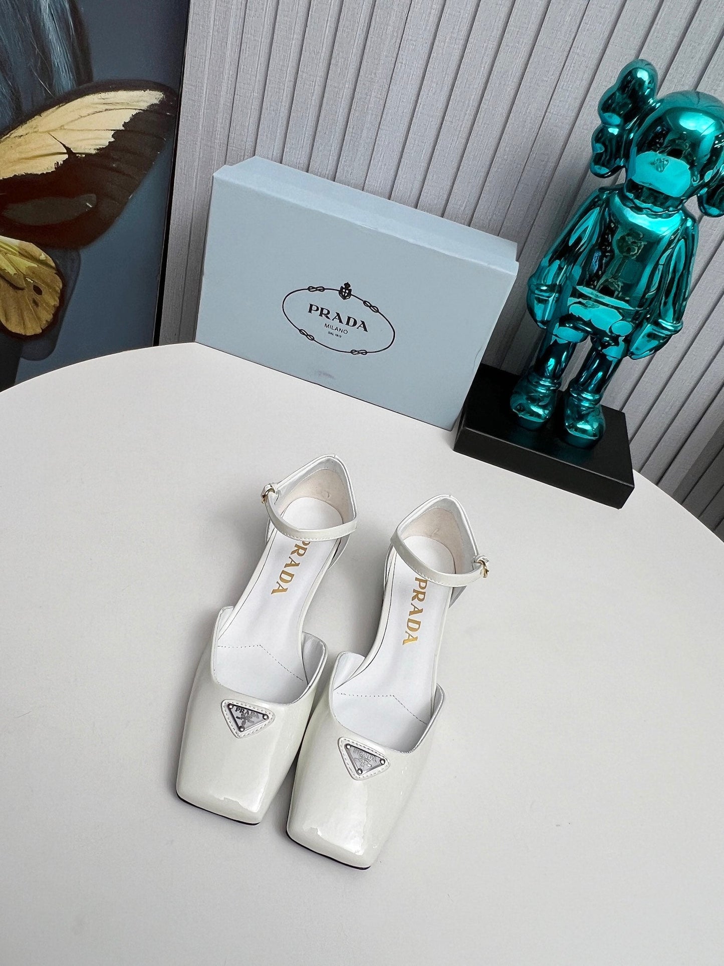 ЖІНОЧІ ТУФЛІ PRADA 26S НА КАБЛУКУ 40 ММ З РЕМІНЦЕМ НА ЩИКОЛОТЦІ З БІЛОЇ ЛАКОВАНОЇ ШКІРИ ТЕЛЯТИ З ЛОГОТИПОМ У ВИГЛЯДІ ТРИКУТНИКА