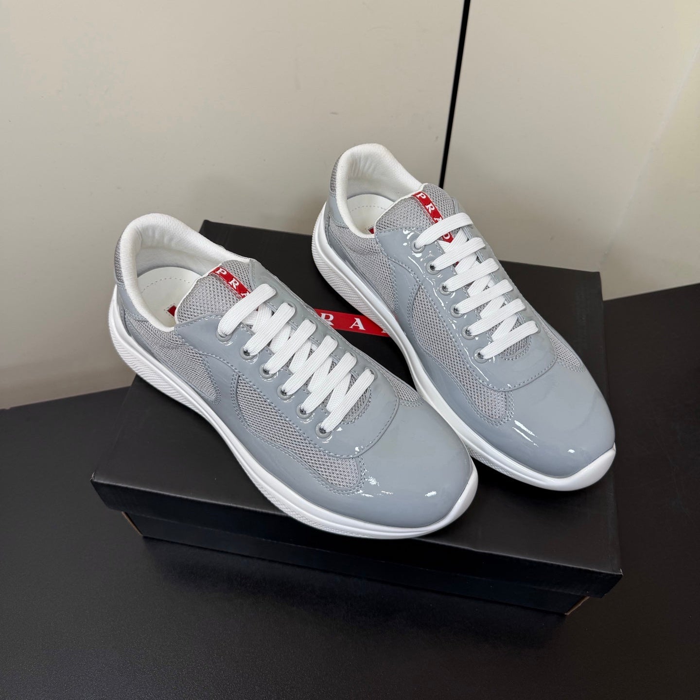 КРОСІВКИ PRADA 26S ЗІ СВІТЛО-СІРОЇ ЛАКОВАНОЇ ТЕЛЯЧОЇ ШКІРИ ТА БІЛОЇ СІТКИ