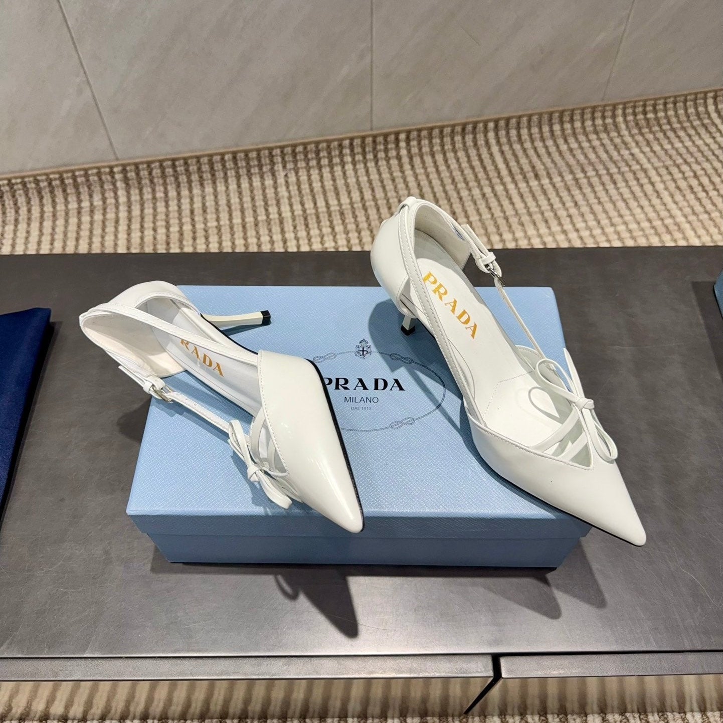 ЖІНОЧІ ТУФЛІ PRADA 26S НА ВИСОКИХ ПІДБОРАХ 75 ММ ІЗ ЗАГОСТРЕНИМ НОСКОМ ТА ВИРІЗАМИ З БІЛОЇ ТЕЛЯЧОЇ ШКІРИ З БАНТОМ
