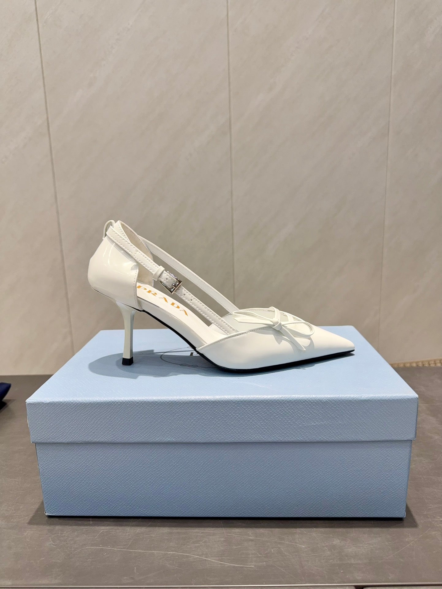 ЖІНОЧІ ТУФЛІ PRADA 26S НА ВИСОКИХ ПІДБОРАХ 75 ММ ІЗ ЗАГОСТРЕНИМ НОСКОМ ТА ВИРІЗАМИ З БІЛОЇ ТЕЛЯЧОЇ ШКІРИ З БАНТОМ